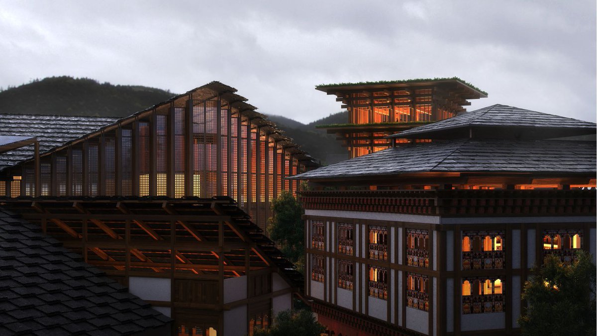 Traditional Bhutanese architecture with illuminated wooden buildings and mountains at dusk